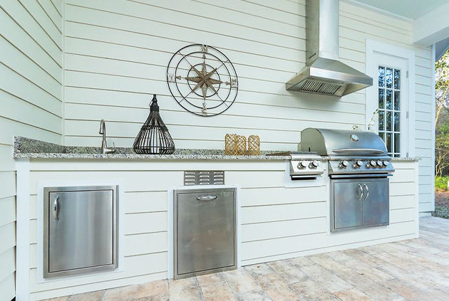 Outdoor kitchen equipped with BBQ, access drawers, outdoor refrigeration, and a sink.